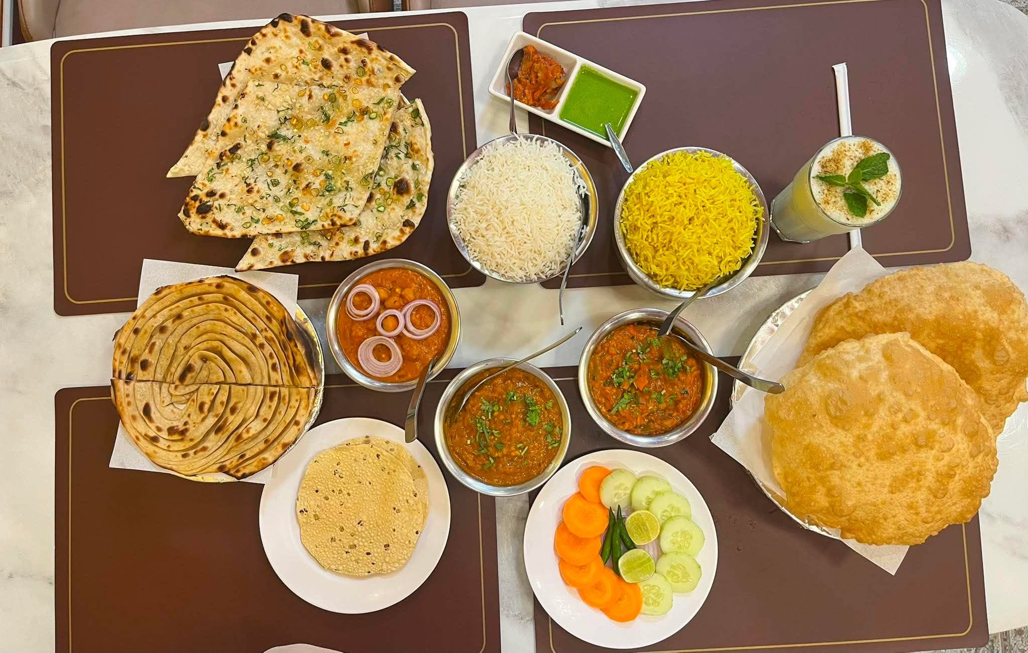 A full Indian thali spread โ naan, rice, curries, papad, salad and lassi at Indian Flavours Indian Food